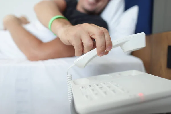 En man lägger på luren medan han ligger i sängen — Stockfoto