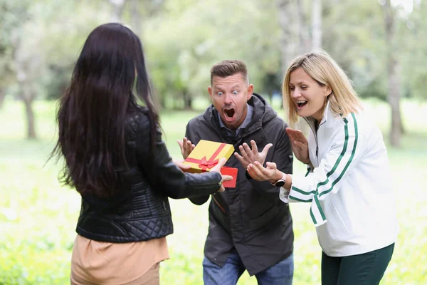 Woman opens gift box and couple looks on happily — Stock Photo, Image