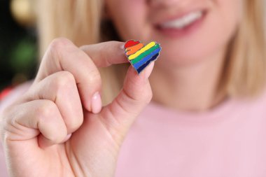 Gülümseyen kadın elinde küçük bir lgbt simgesi tutuyor.