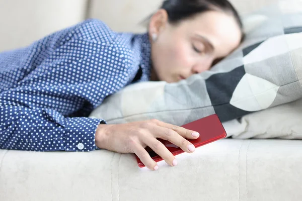 Mujer duerme en el sofá y sostiene el teléfono inteligente — Foto de Stock