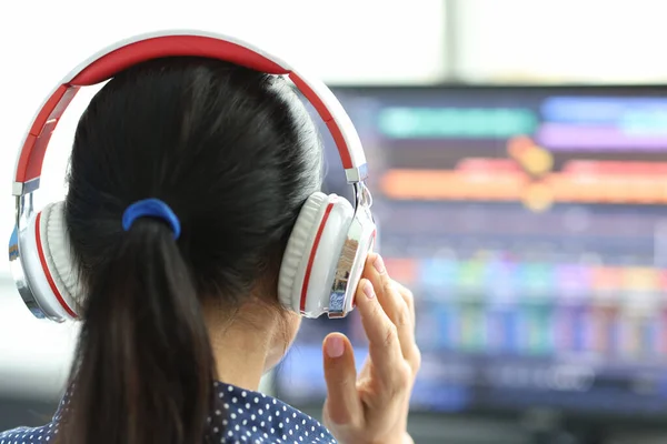 Woman in headphones in front of computer monitor — стоковое фото