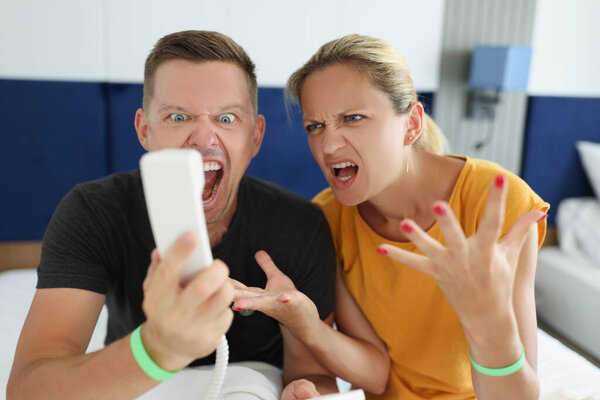 Мужчина и женщина кричат в телефон в номере отеля