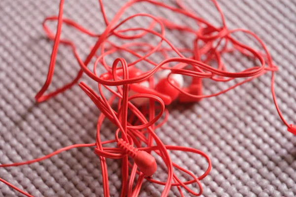 Tangled red wired headphones on gray background — стоковое фото