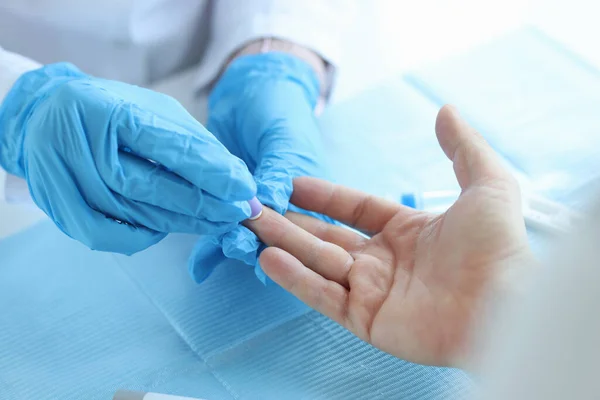 Técnico de laboratório de enfermagem em luvas, usando escarificador indolor para picar o dedo do paciente — Fotografia de Stock