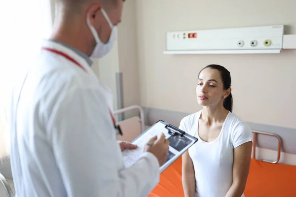 Doctor in mask communicates with patient in clinic — стоковое фото