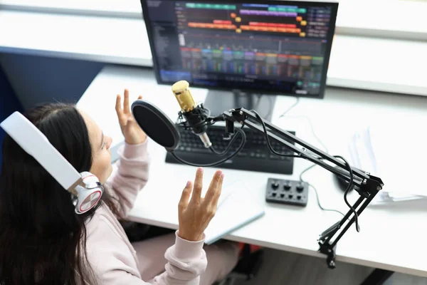 Woman in headphones in front of microphone broadcasts radio — стоковое фото