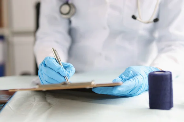 Доктор в рукавичках заповнює медичні документи на кишені — стокове фото
