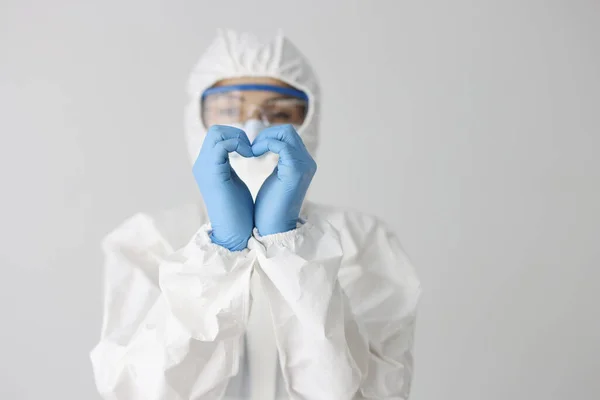 Doctor in protective suit makes heart gesture with hands — ストック写真