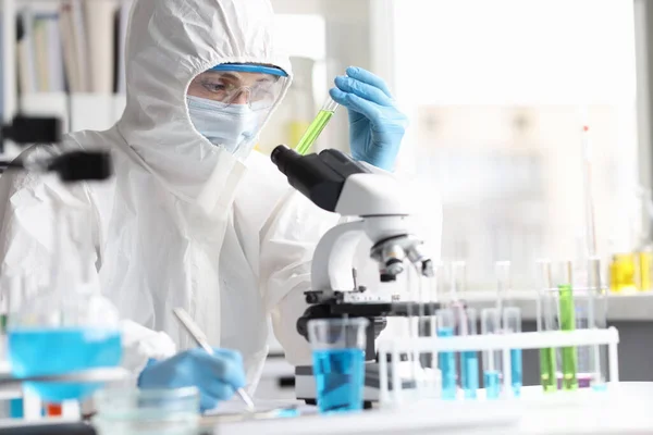 Cientista em terno de proteção estuda líquidos tóxicos venenosos em laboratório — Fotografia de Stock