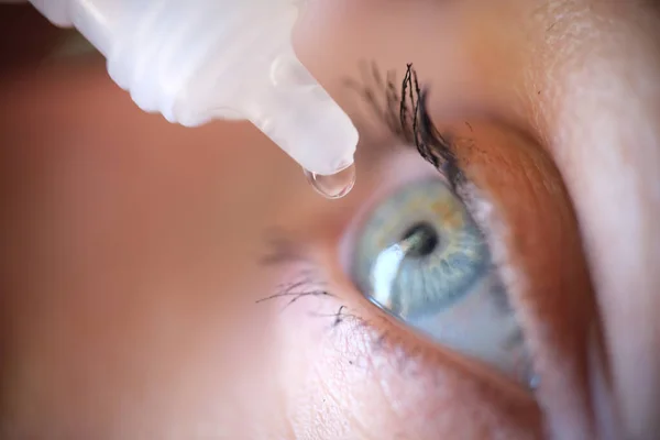 Drops from vial dripping into woman eye closeup — ストック写真