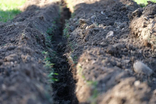 Excavated trench in lawn for laying irrigation system closeup — Photo