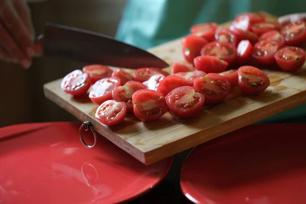 Cook legt geschnittene Tomaten auf rotem Teller Nahaufnahme — Stockfoto