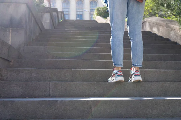 Κουρασμένη γυναίκα σε sneakers στέκεται μπροστά από μεγάλη σκάλα με σκαλοπάτια — Φωτογραφία Αρχείου