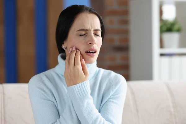 Молодая женщина с острой зубной болью на диване — стоковое фото