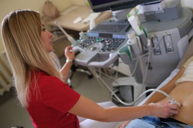 Gynecologist performs ultrasound scan on young woman with problems of female reproductive system