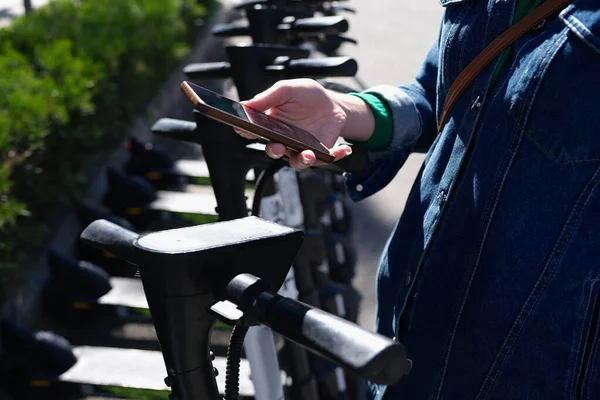 Kobieta płacąca czynsz skutera elektrycznego za pomocą aplikacji mobilnej na ulicy — Zdjęcie stockowe