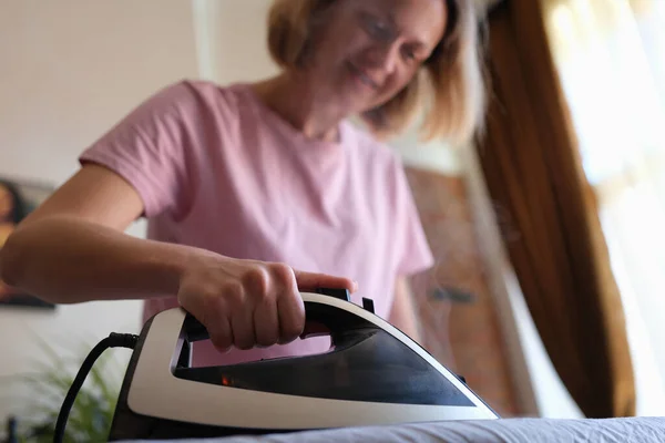Woman irons clothes with iron on ironing board — Stock Fotó