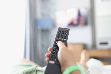 Watching TV with remote control in hand closeup