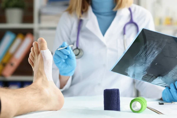 Lékař kontroluje rentgen nohou pacienta se zraněním — Stock fotografie