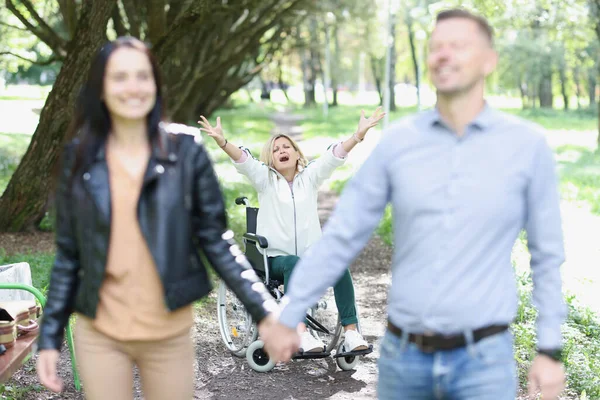 Abandoned disabled woman sits in wheelchair in park stretches arms forward and shouts no — Stok fotoğraf