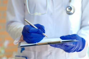 Doktor elinde kalem ve hasta kayıt belgeleriyle panoyu klinikte tutuyor.