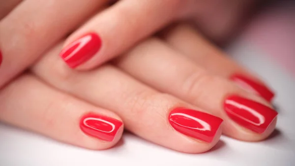 Red bright beautiful varnish on female hands closeup — Stock Photo, Image
