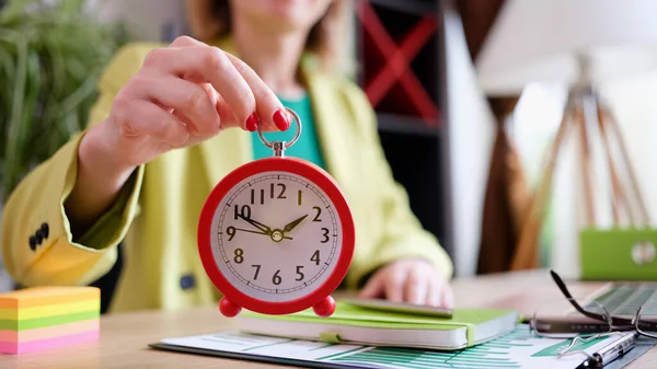 Businesswoman holding red alarm clock at workplace — Stock Photo, Image