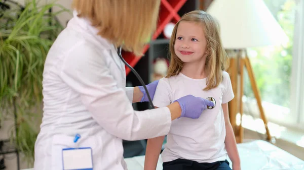 Doctor pediatrician listens with stethoscope to heartbeat of little girl in clinic — Zdjęcie stockowe