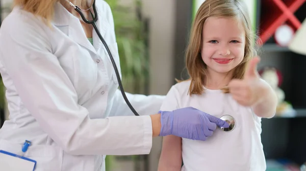 Menina criança fazendo polegares para cima gesto na consulta médica — Fotografia de Stock