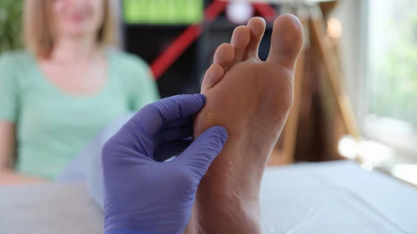 Orthopedist performs examination of leg with skin problem.