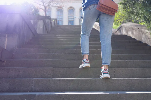 Woman in jeans going up steep stairs