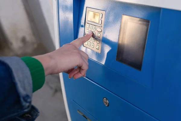 Woman paying for parking at teller machine in city