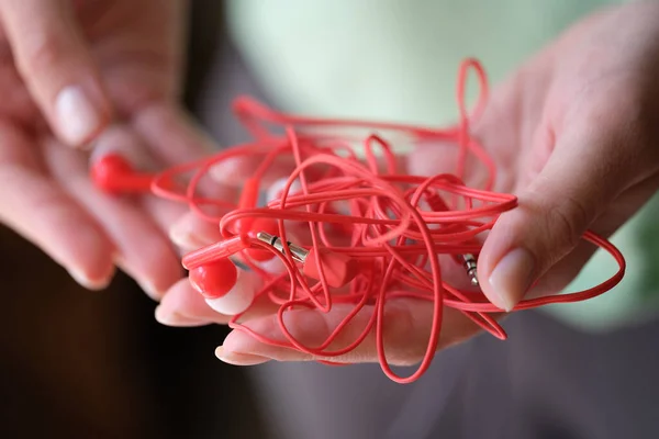 Woman holding red tangled earphone, headphone mess — Φωτογραφία Αρχείου