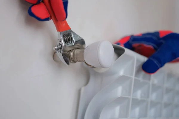 Plumber installing heating radiator in apartment or house — Stock fotografie