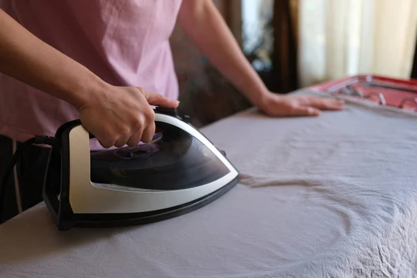 Housewife irons bed linen on ironing board — Stock Fotó