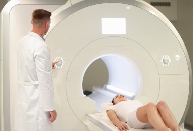 Tıbbi laboratuvarda erkek radyologlar kadın hastalarla MRI veya CT taramalarını kontrol ederler.