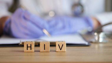 Doktor, ahşap küplerin arka planına HIV kapaklı reçete yazıyor.
