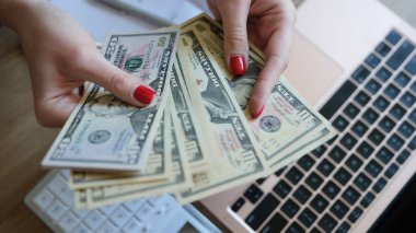 Kadın, evinde internetten bilgisayarla çalışarak kazandığı dolarları tutuyor.