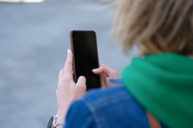 Sokakta kadın akıllı telefonu elinde tutuyor.