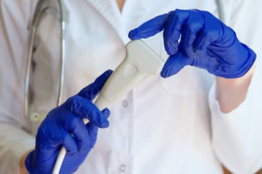 Doktor klinikte ultrason tarayıcısı tutuyor.