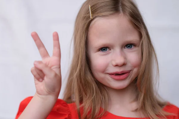 Portret van klein blond meisje met twee vingers gebaar. — Stockfoto