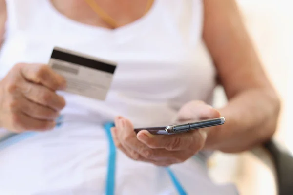 Starsza kobieta dokonuje zakupów w Internecie na smartfonie i płaci kartą kredytową — Zdjęcie stockowe