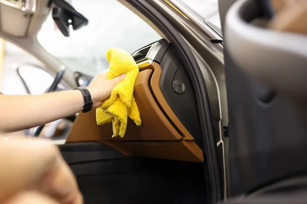 Close-up of male hand cleaning vehicle interior, cleaner washes car leather salon. Cleaning service, or self-service car wash, removing of dust concept