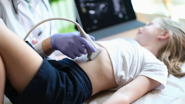 Close-up of practitioner examines with ultrasound of internal organs of little girl in clinic. Ultrasound of abdominal cavity procedure concept