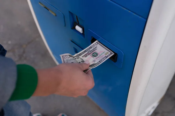 Close-up of woman paying for parking using cash at teller machine. Parking fee, operated ticket machine or pay station concept
