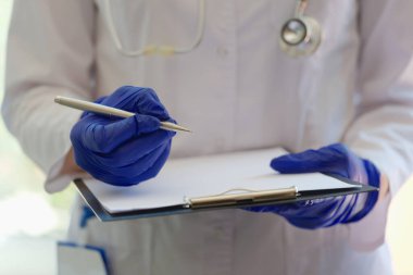 Pratisyen hekimin elinde dosya tutarken ve hasta hakkında bilgi toplarken yakın plan çekimleri. Hastalık geçmişi. Tıp ve sağlık hizmetleri kavramı