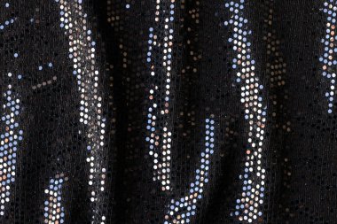 Renkli pullu siyah kumaşın üst görünümü soyut arka plan. Şık dalgalı kumaş dokusu arkaplanı