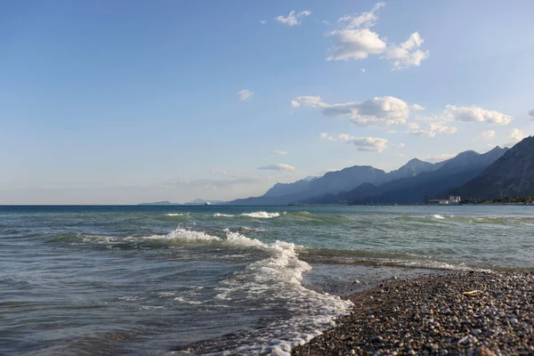 Deniz burnu ve beyaz köpüklü çakıl taşı plajı. Denizde sıcak bir yaz günü