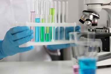 Bilim adamı laboratuarda mavi yeşil sıvılarla test tüpleri tutuyor. Kimya ve tıp araştırma konsepti