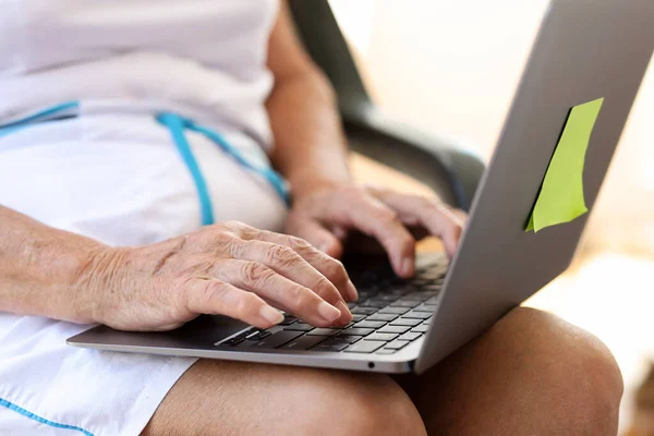 Elderly woman typing on laptop is looking for information on Internet. Online leisure or work for pensioners concept